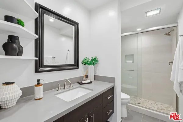 a bathroom with a granite countertop sink toilet a mirror and shower