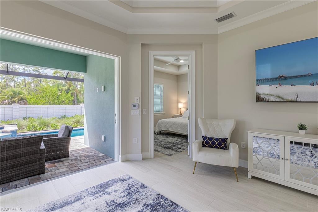 8909 Yucatan Court Naples, FL 34113 - Photo 7 of 36 Bedroom with a tray ceiling, light wood finished floors, access to outside, and ornamental molding