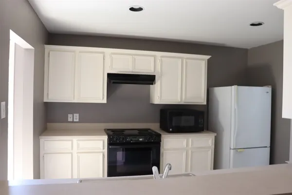 a kitchen with a refrigerator stove and white cabinets