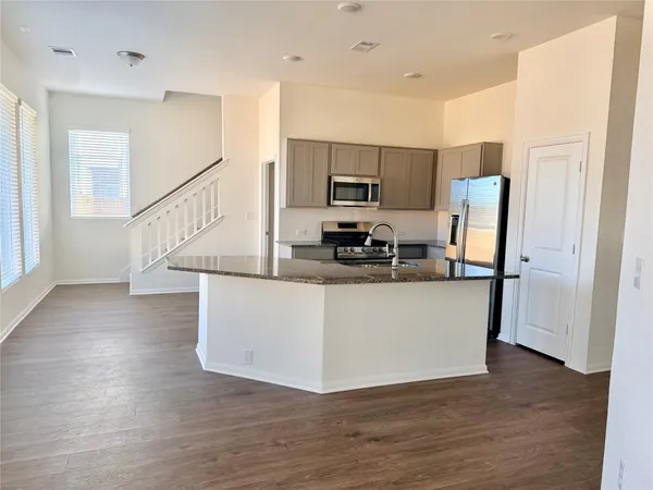 a living room with stainless steel appliances wooden floor and a view of kitchen