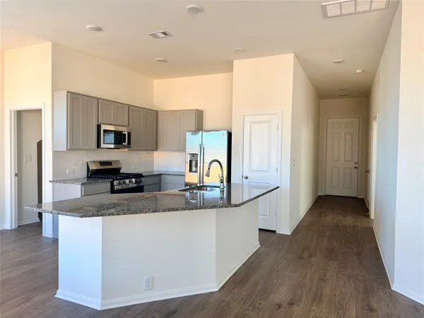 a large kitchen with granite countertop a sink a counter top space and cabinets