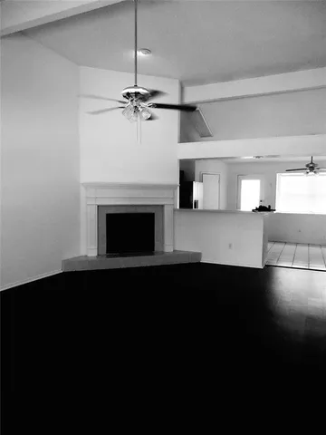 a view of a livingroom with a fireplace a ceiling fan and a hardwood floor