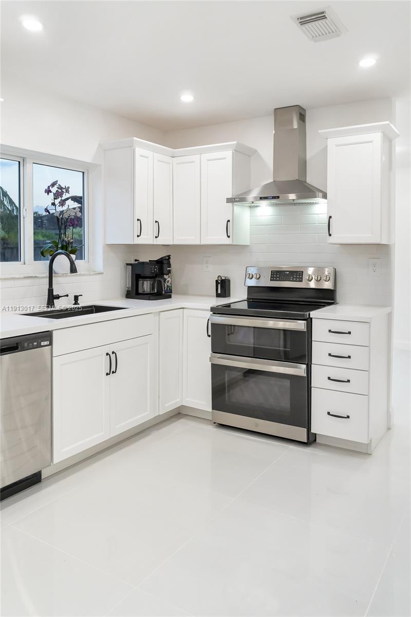 15309 Southwest 183rd Terrace Miami, FL 33187 - Photo 7 of 30 a kitchen with stainless steel appliances a stove sink and cabinets