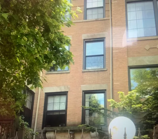 a view of a brick house with a large windows and a table and chairs