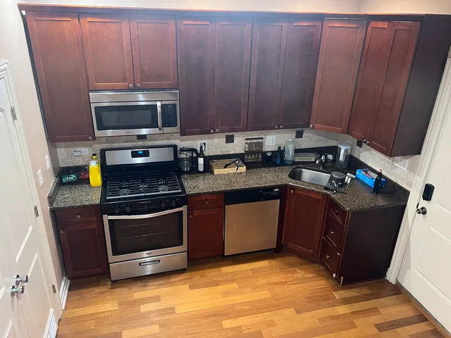 a kitchen with stainless steel appliances granite countertop wooden cabinets a stove top oven a sink and dishwasher