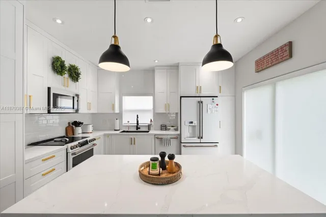 a kitchen with stainless steel appliances granite countertop a sink and white cabinets