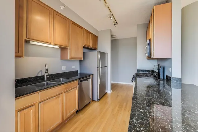 a kitchen with granite countertop a sink stainless steel appliances and cabinets