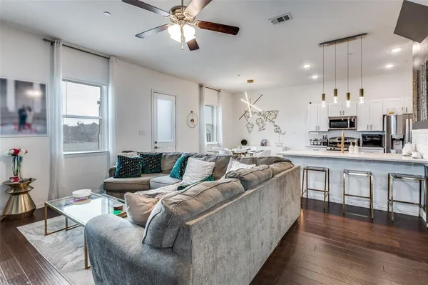 a living room with furniture kitchen and a wooden floor