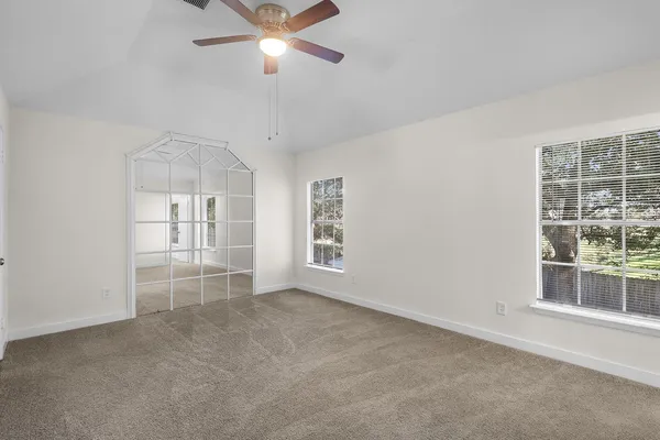 en empty room with windows and ceiling fan