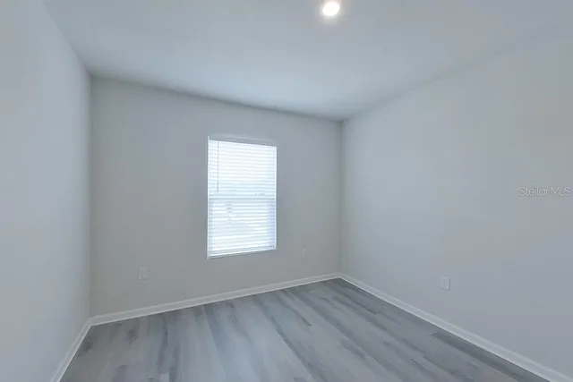an empty room with wooden floor and window
