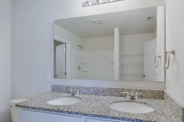 a bathroom with a granite countertop sink and a mirror