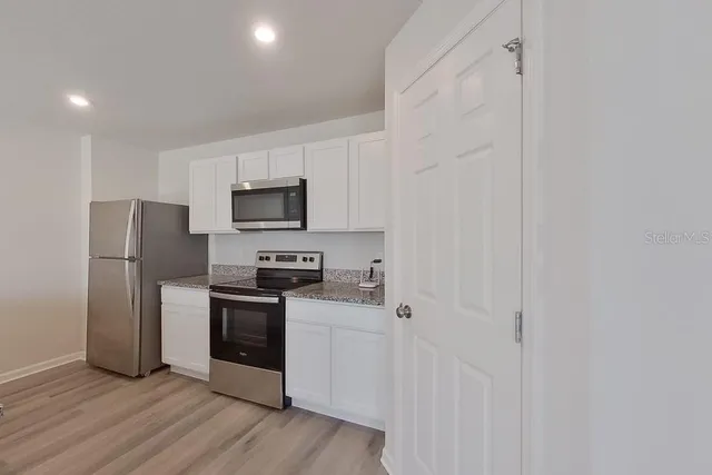 a kitchen with a refrigerator stove and wooden cabinets