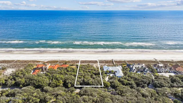 an aerial view of a house and a yard and ocean view