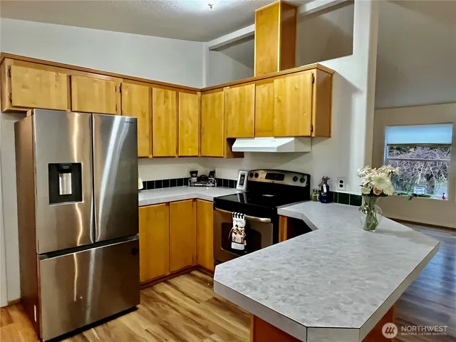 a kitchen with stainless steel appliances granite countertop a refrigerator sink and stove