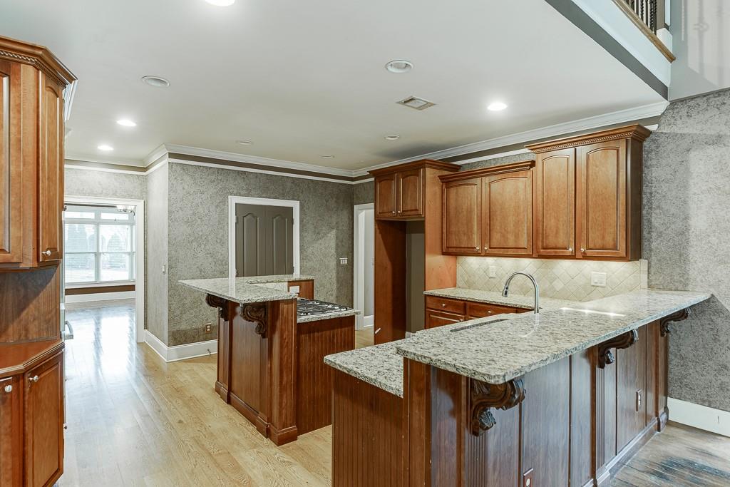 940 Chateau Forest Road Hoschton, GA 30548 - Photo 22 of 87 a kitchen with granite countertop cabinets and wooden floor