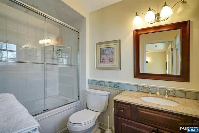 a bathroom with a granite countertop toilet a sink and a mirror