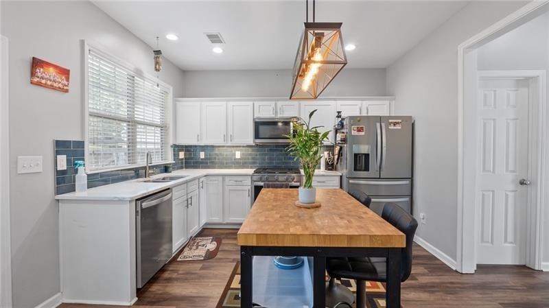 3525 Elder Field Lane Cumming, GA 30040 - Photo 11 of 45 a kitchen with stainless steel appliances kitchen island granite countertop a table chairs in it and wooden floors