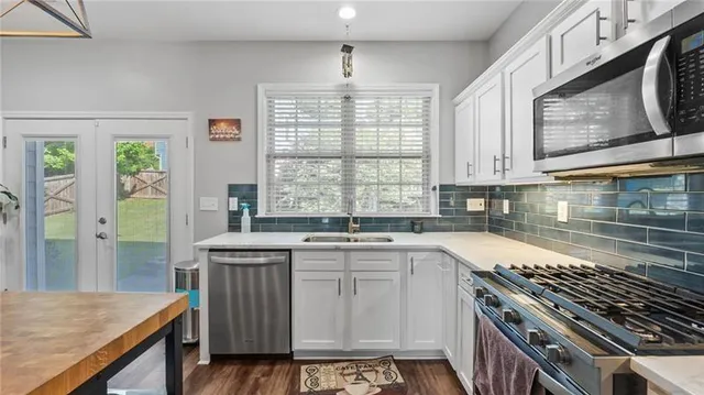 a kitchen with stainless steel appliances kitchen island granite countertop a table chairs in it and wooden floors