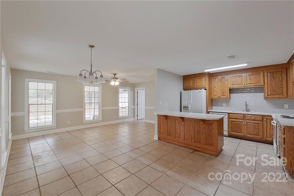 3804 Dusty Hollow Road Monroe, NC 28110 - Photo 21 of 42 a large kitchen with kitchen island granite countertop a stove a sink dishwasher and white cabinets with wooden floor