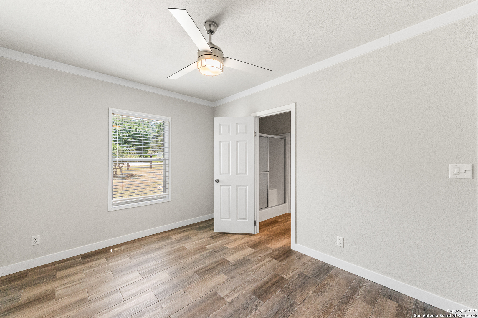 9130 Rebecca Creek Road Spring Branch, TX 78070 - Photo 34 of 77 an empty room with wooden floor ceiling fan and windows