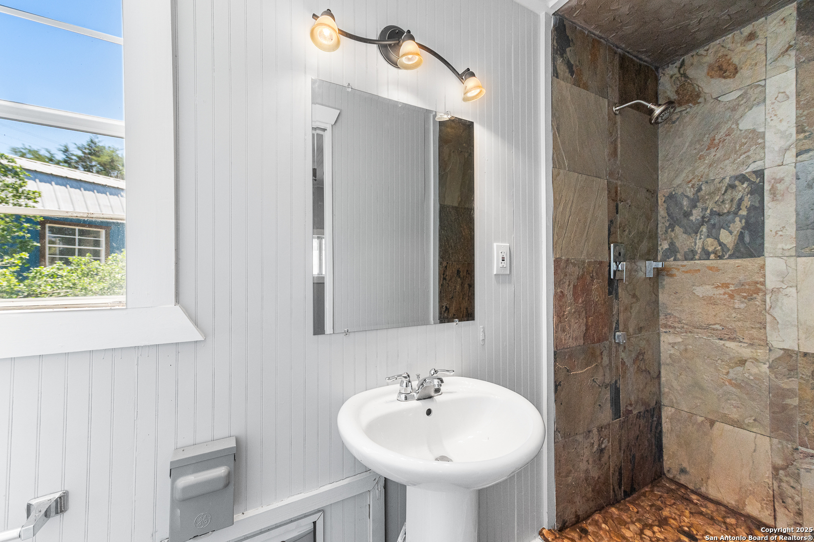 9130 Rebecca Creek Road Spring Branch, TX 78070 - Photo 56 of 77 a bathroom with a sink a mirror and shower