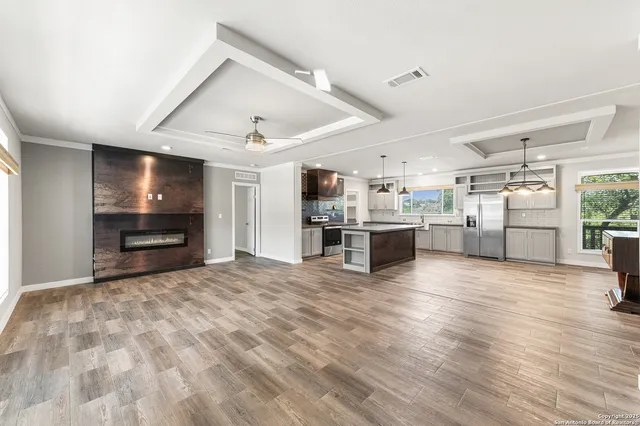 a large kitchen with stainless steel appliances kitchen island granite countertop a large counter top and wooden floors