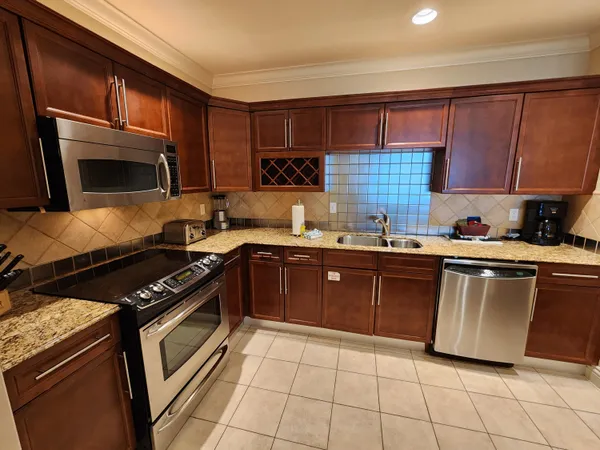 a kitchen with granite countertop a table chairs microwave and refrigerator