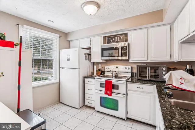 a kitchen with granite countertop a refrigerator a stove and a sink