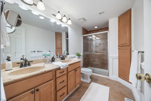 a bathroom with a double vanity sink a toilet a mirror and shower