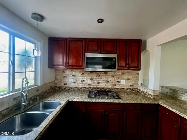 a kitchen with granite countertop a sink and a stove top oven