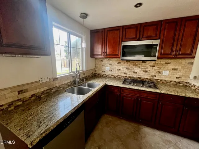 a kitchen with stainless steel appliances granite countertop a sink stove and microwave
