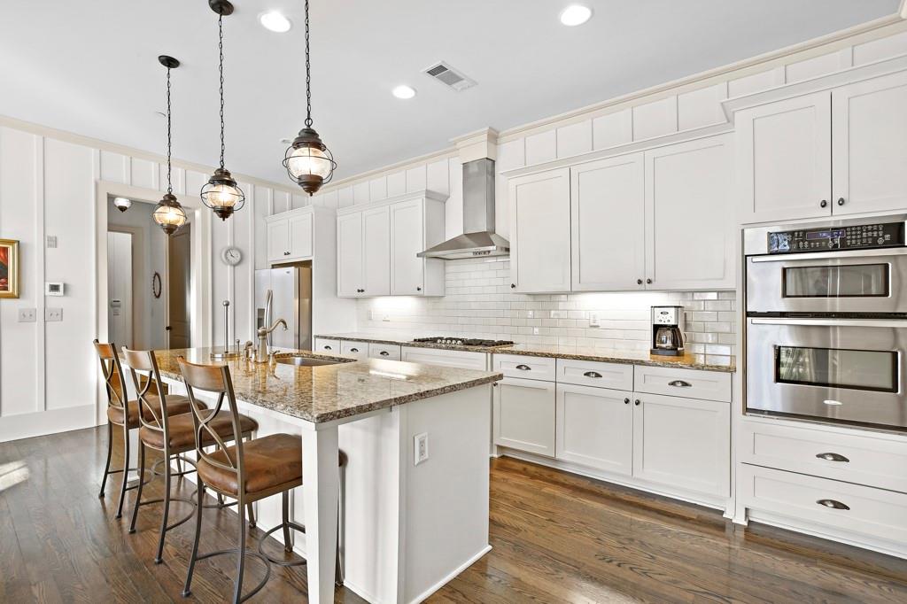 402 Prosper Circle, Unit 102 Marietta, GA 30060 - Photo 14 of 72 a kitchen with stainless steel appliances kitchen island granite countertop a table chairs and white cabinets