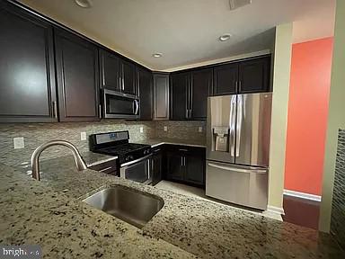 a kitchen with granite countertop stainless steel appliances a refrigerator and a sink