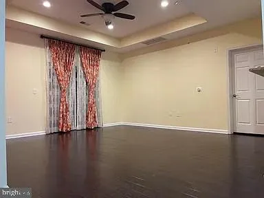 an empty room with wooden floor and a ceiling fan