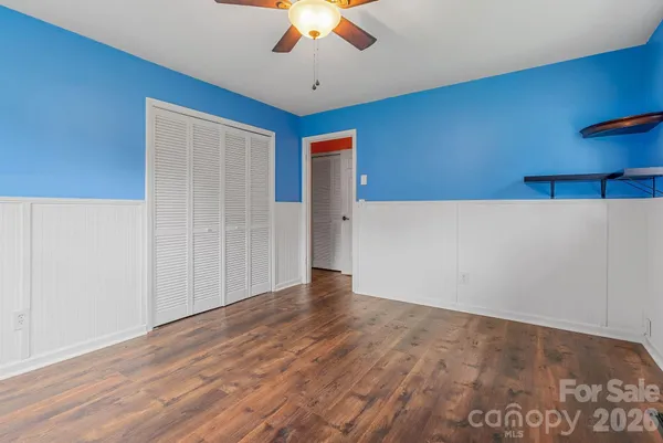an empty room with wooden floor closet and chandelier fan