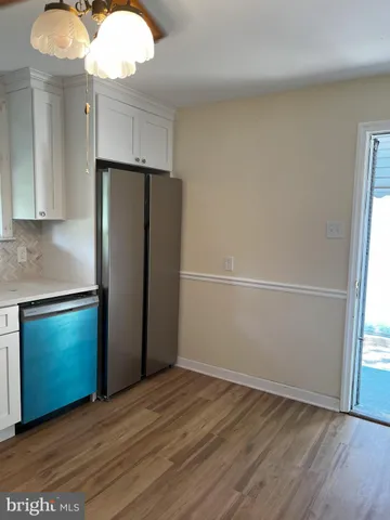 an empty room with wooden floor cabinet and stainless steel appliances