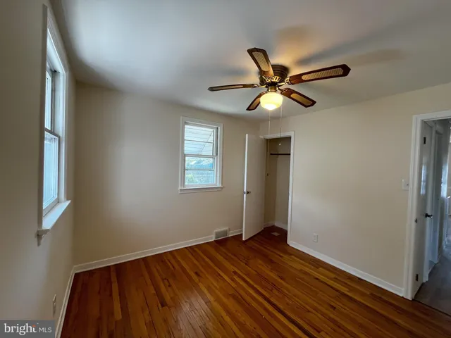 a view of an empty room with window and wooden floor
