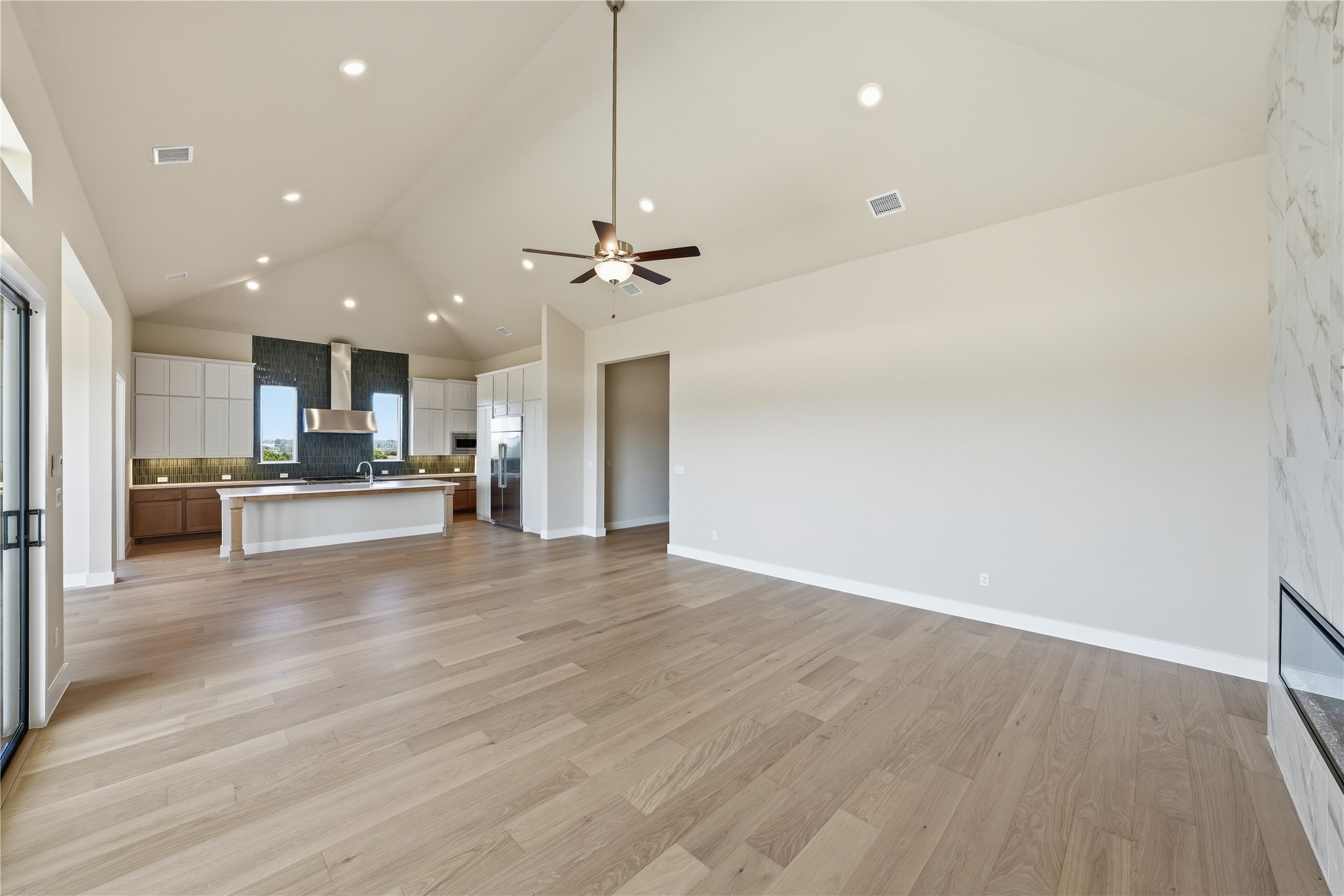 1209 Doelling Drive Georgetown, TX 78633 - Photo 6 of 31 Unfurnished living room with light wood-style floors, a ceiling fan, a high ceiling, and recessed lighting