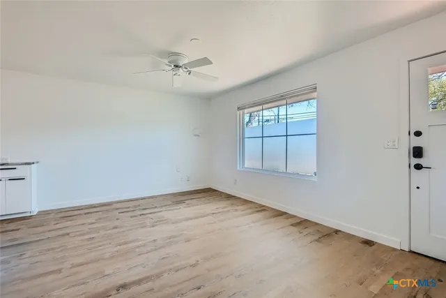 an empty room with windows and fan