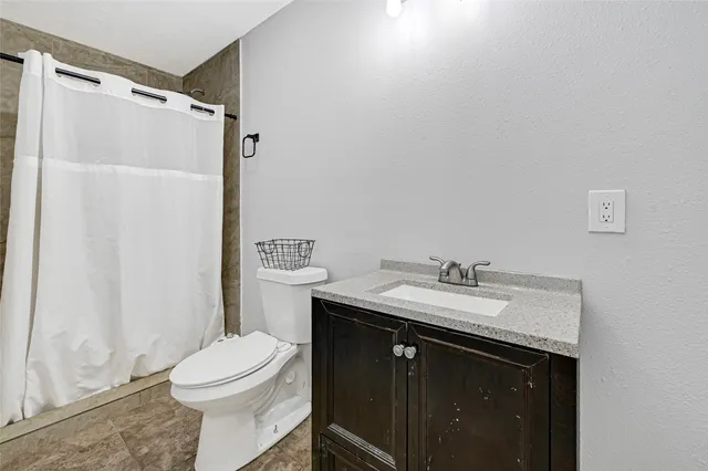 a bathroom with a granite countertop sink toilet and shower