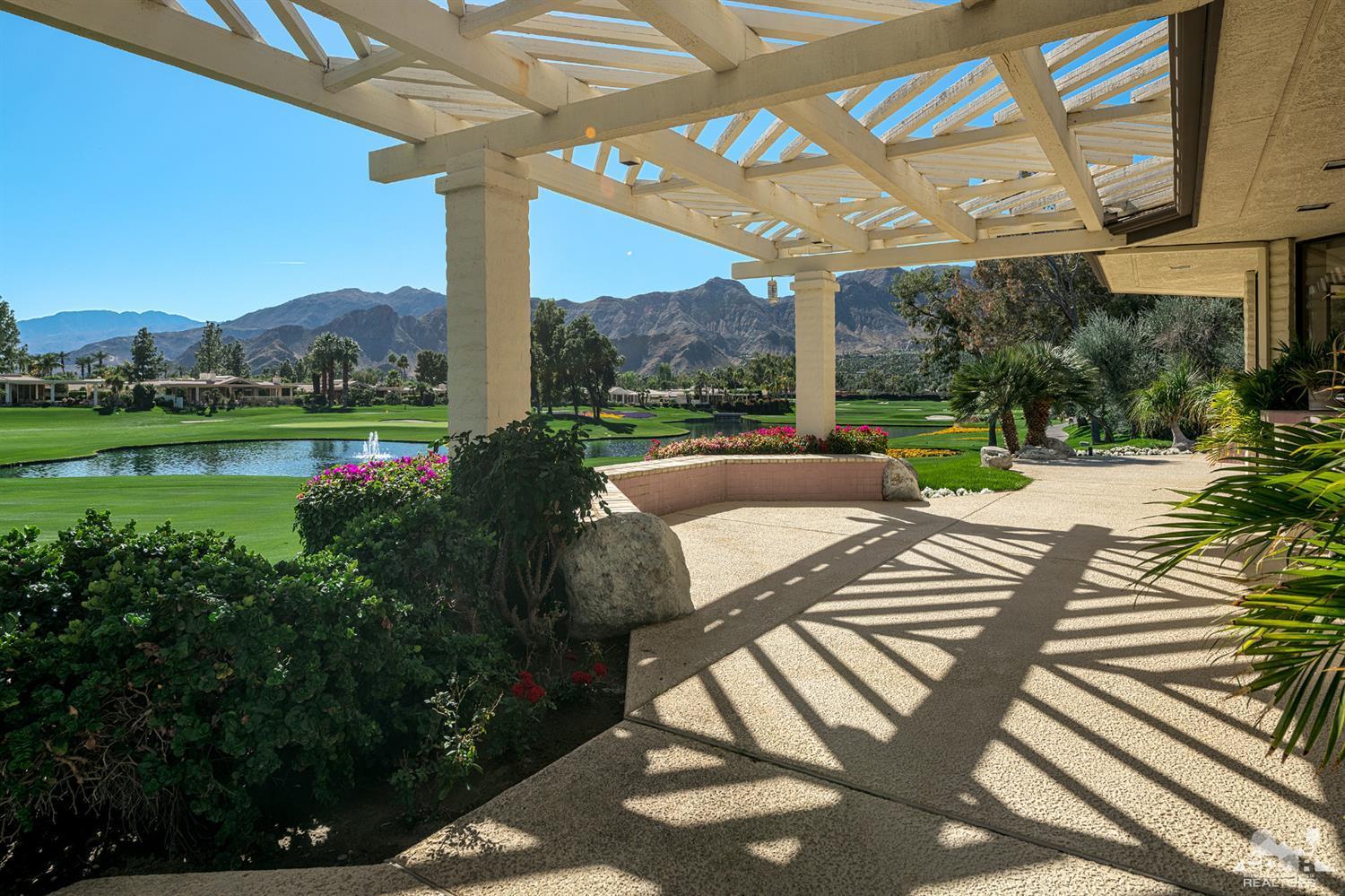 a view of a patio with a table chairs potted plants and palm trees