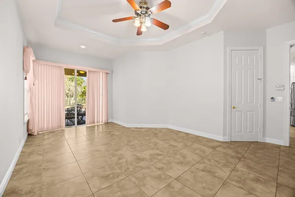 an empty room with chandelier fan and windows