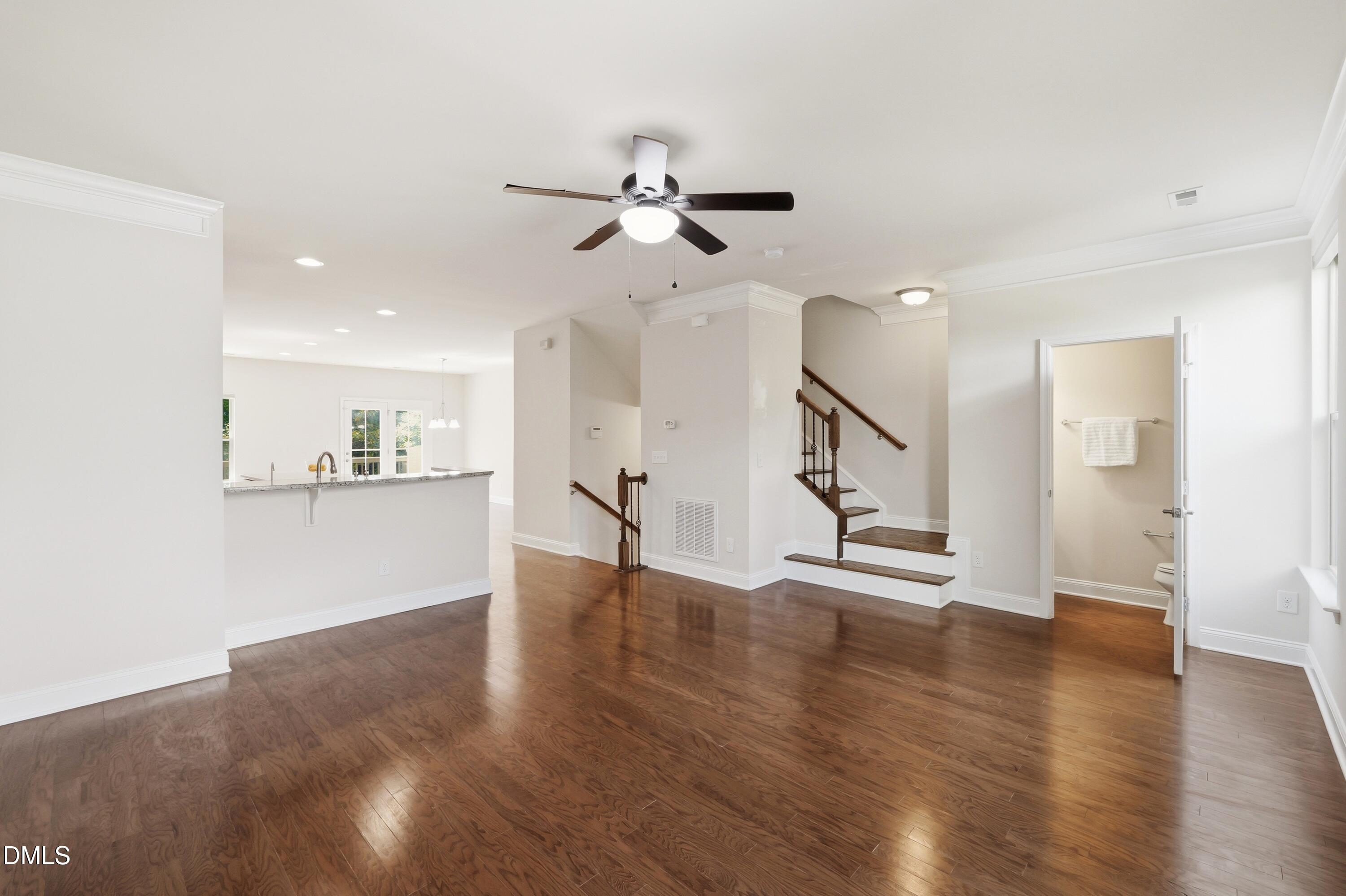 1004 Waymaker Court Apex, NC 27502 - Photo 4 of 30 a view of an empty room with wooden floor and a kitchen view