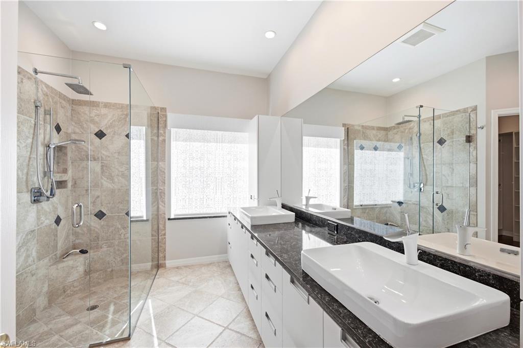 1960 Timarron Way Naples, FL 34109 - Photo 28 of 45 Spacious Master bathroom featuring a glass-enclosed shower with tiled walls and a rain shower head
