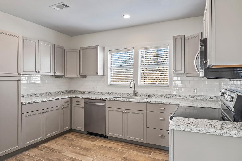 442 West McCart Street Krum, TX 76249 - Photo 12 of 40 a kitchen with granite countertop sink stove and cabinets