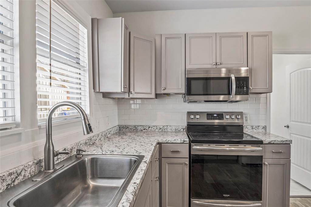 442 West McCart Street Krum, TX 76249 - Photo 13 of 40 a kitchen with stainless steel appliances granite countertop a sink stove and microwave
