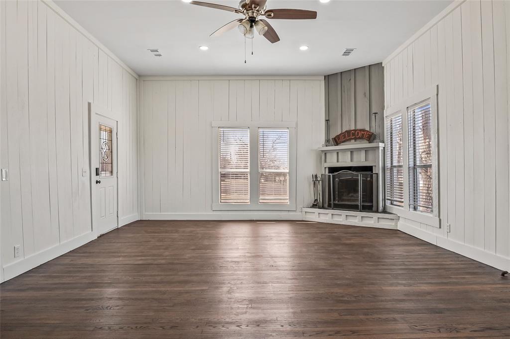 442 West McCart Street Krum, TX 76249 - Photo 3 of 40 an empty room with wooden floor fireplace and windows