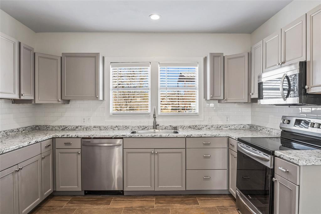 442 West McCart Street Krum, TX 76249 - Photo 4 of 40 a kitchen with stainless steel appliances granite countertop white cabinets sink and window
