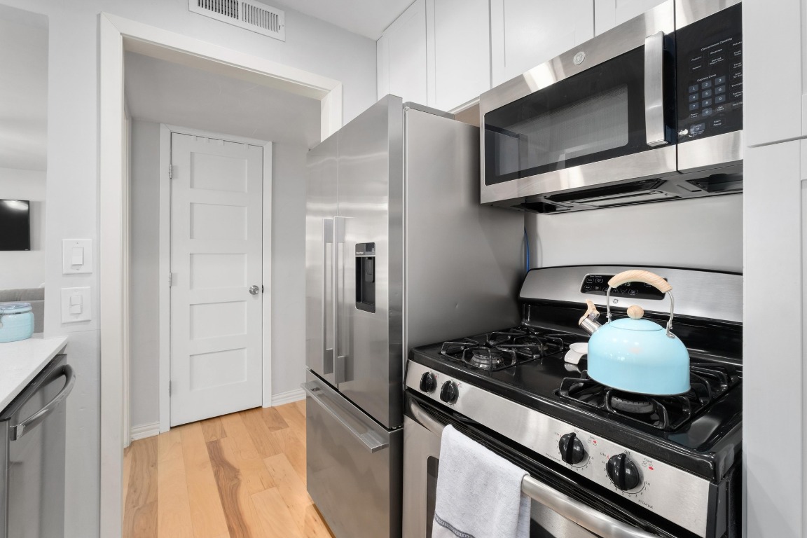 1210 Windsor Road, Unit 122 Austin, TX 78703 - Photo 13 of 24 Kitchen featuring stainless steel appliances, light wood-style floors, and white cabinetry