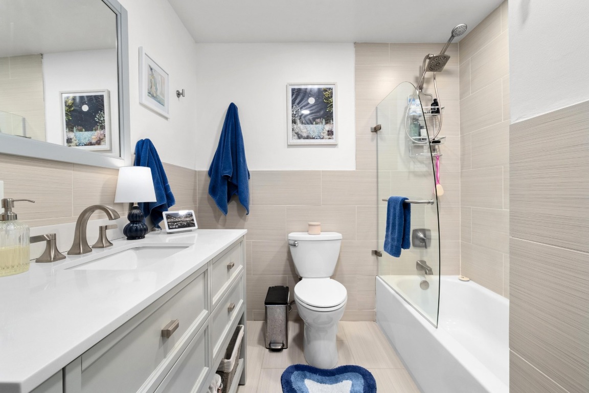1210 Windsor Road, Unit 122 Austin, TX 78703 - Photo 20 of 24 Full bath with vanity, shower / washtub combination, tile walls, wainscoting, and light tile patterned floors